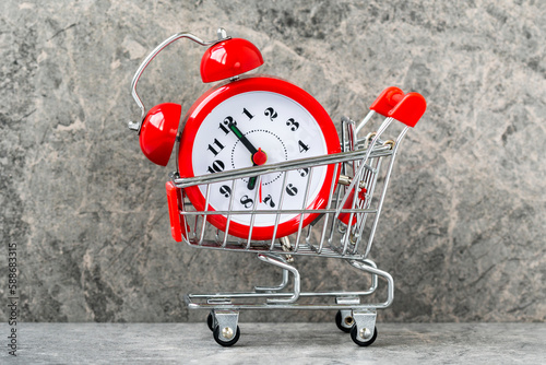 Buying time concept with clock and shopping cart photo