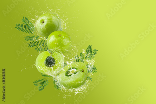 Creative layout made from Fresh Sliced Emblic or Indian gooseberry and water Splashing on a green background.