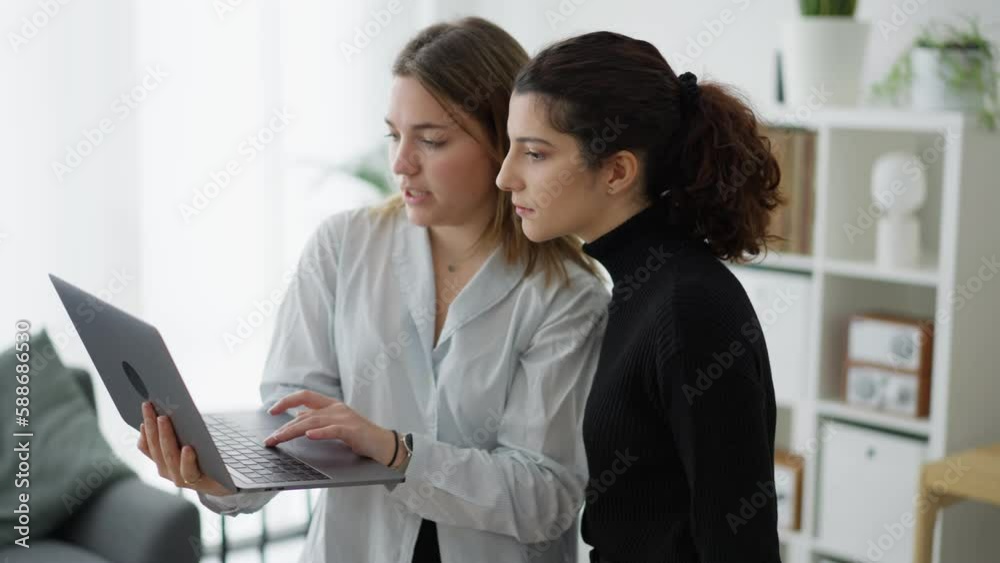 Positive young female in casual clothes and eyeglasses browsing netbook while working on project in creative workspace together Positive young female in casual clothes and eyeglasses browsing netbook while working on project in creative workspace together