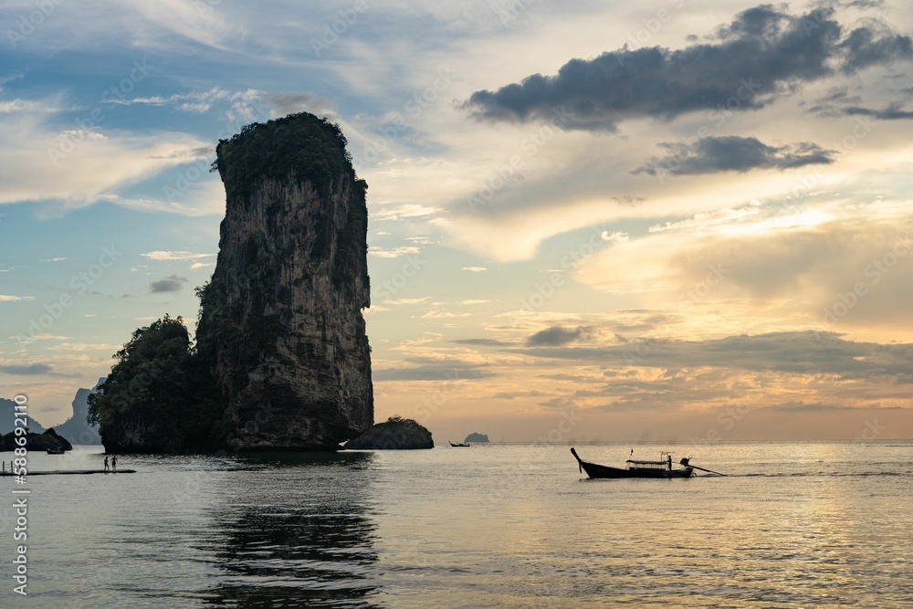 Huge stack and a boat at the Pai Plong Beach with sunset in the background in Krabi, Thailand
