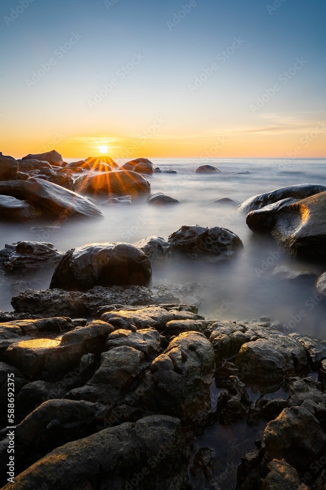 Naklejka premium Vertical shot of the rocky coast in Khlong Chao beach, Thailand on sunset