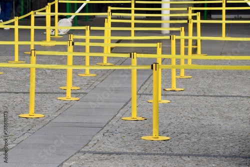 Yellow queue tape over paved area. Paris, France, March 2023.