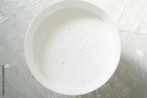 Bucket of white color paint onagainst background floor