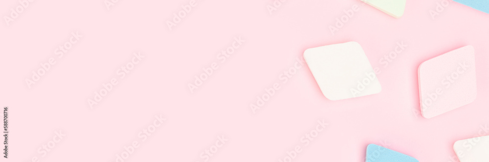 Banner with makeup sponges scattered on a pink background. Place for text.