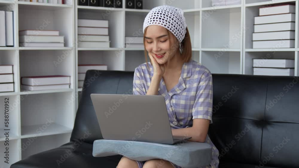Asian women are using laptops for watching online movies on the sofa in the living room. She is happy and enjoying on weekend. Asian women are using laptops for watching online movies on the sofa in the living room. She is happy and enjoying on weekend.