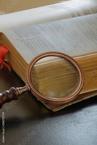 Closeup of an antique magnifying glass rest on an ancient book