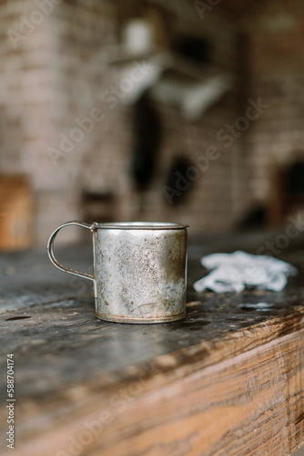 Vertical shot of an old tin cup on a wooden table in a kitchen
