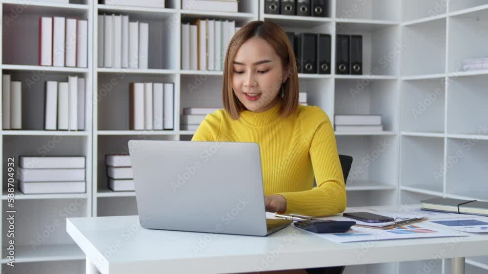 Happy excited successful business asian woman triumphing in office, Portrait of a cheerful Asian businesswoman sitting at the table in office Happy excited successful business asian woman triumphing in office, Portrait of a cheerful Asian businesswoman sitting at the table in office