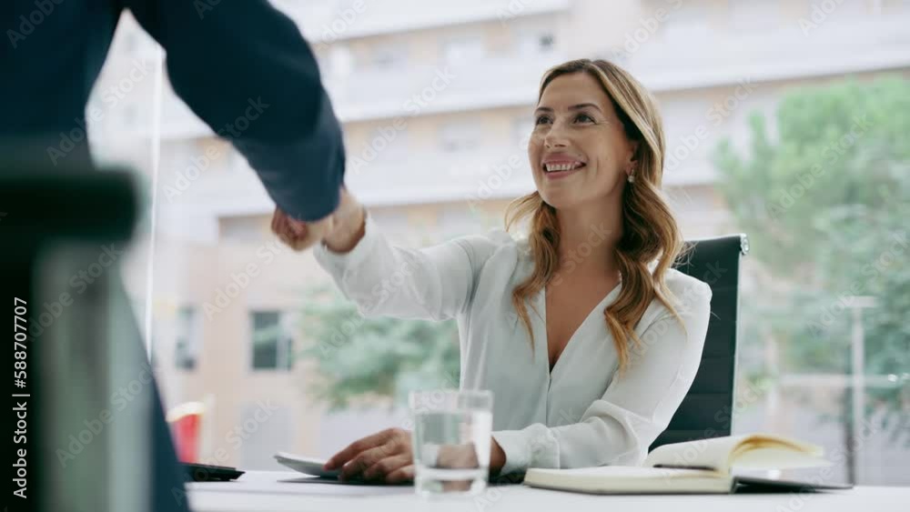 Video of two attractive business people shaking their hands while smiling after signing new contract in modern office. Video of two attractive business people shaking their hands while smiling after signing new contract in modern office.