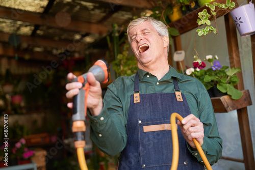 Fototapete Älterer Gärtner mit Gartenschlauch beim laut Singen