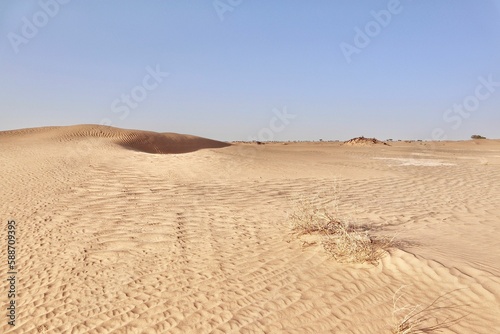 Scenic view of desert against sky under the clear blue sky with the sun shining bright