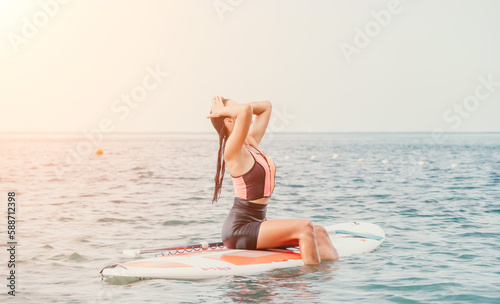 Sea woman sup. Silhouette of happy young woman in pink bikini, surfing on SUP board, confident paddling through water surface. Idyllic sunset. Active lifestyle at sea or river. © panophotograph