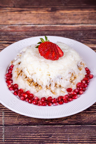 G  lla   dessert with pomegranate and strawberry. Ramadan dessert. Gullac dessert with walnuts on wooden background. Close up