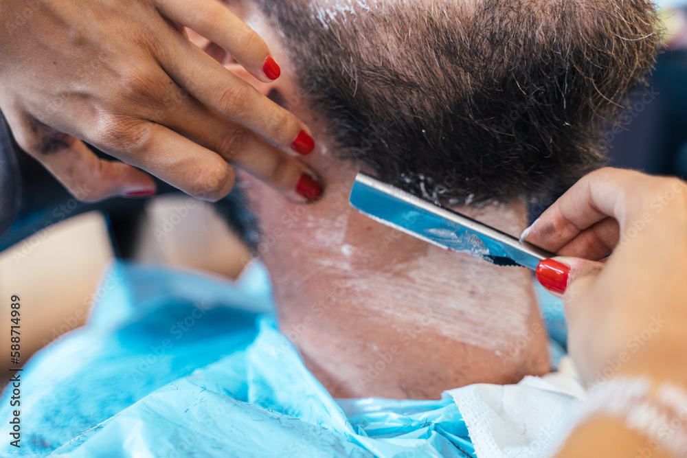 Hairdresser shaving a client with a manual razor Hairdresser shaving a client with a manual razor