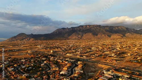 Aerial drone golden sunset toward Sandia Mountains Albuquerque New Mexico with adobe homes pan up photo
