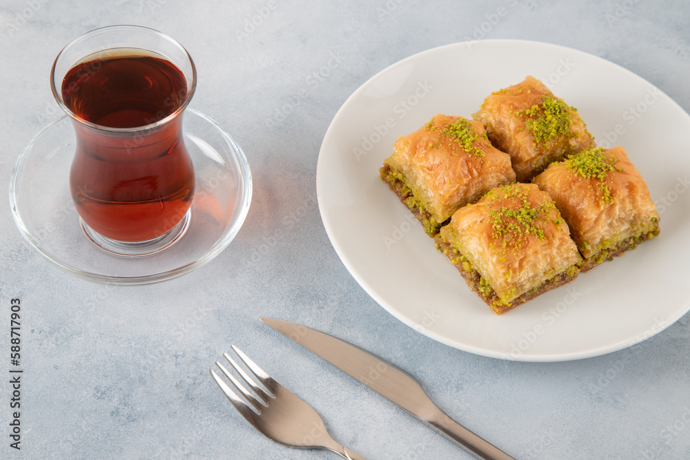 Pistachio baklava on a white plate with Turkish tea.A plate of traditional baklava on light blue background
Pistachio baklava on a white plate with Turkish tea.A plate of traditional baklava on light blue background