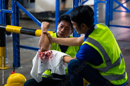 First Aid. Engineering supervisor helping to give first aid to the injured foreman his coworker lying unconscious at industrial factory. Professional engineering teamwork concept.