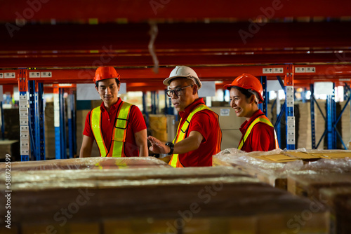 Group of team warehouse asian workers wearing safety hardhats helmet walking in warehouse of Wholesale Merchandise. shelves, pallets and boxes
