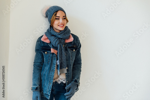 a woman with a warm hat with a scarf in winter clothes stands on a white background