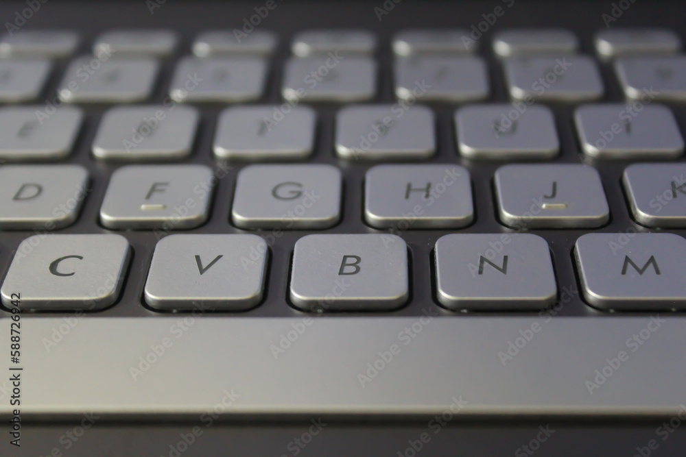 Closeup shot of a laptop keyboard. Keys are gray colour and fonts are block color, Selective focus. Closeup shot of a laptop keyboard. Keys are gray colour and fonts are block color, Selective focus.