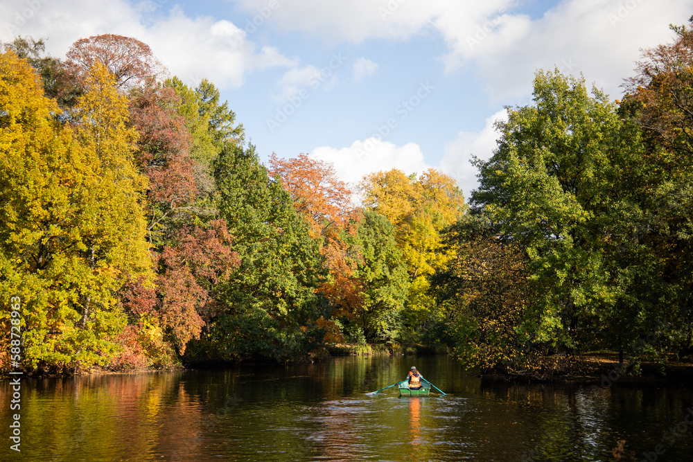 Fototapeta premium Couple rowing a boat on the lake in autumn park