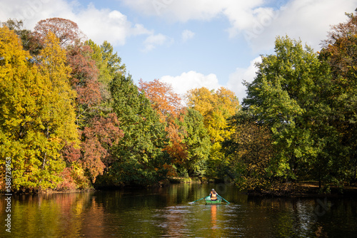 Couple rowing a boat on the lake in autumn park