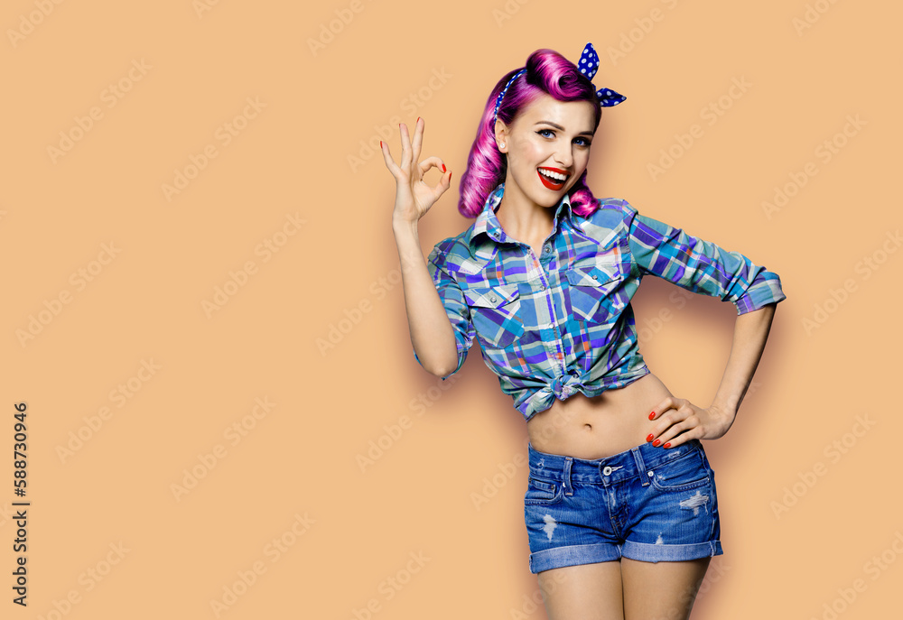 Pin up girl. Portrait photo of excited cheerful smiling red purple hair woman show ok okay hand sign gesture. Retro and vintage concept. Latte beige background. Female model at studio. Pin up girl. Portrait photo of excited cheerful smiling red purple hair woman show ok okay hand sign gesture. Retro and vintage concept. Latte beige background. Female model at studio.