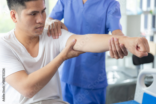 Doctor or Physiotherapist working examining treating injured arm of athlete male patient, stretching and exercise, Doing the Rehabilitation therapy pain in clinic.