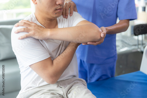 Doctor or Physiotherapist working examining treating injured arm of athlete male patient  stretching and exercise  Doing the Rehabilitation therapy pain in clinic.