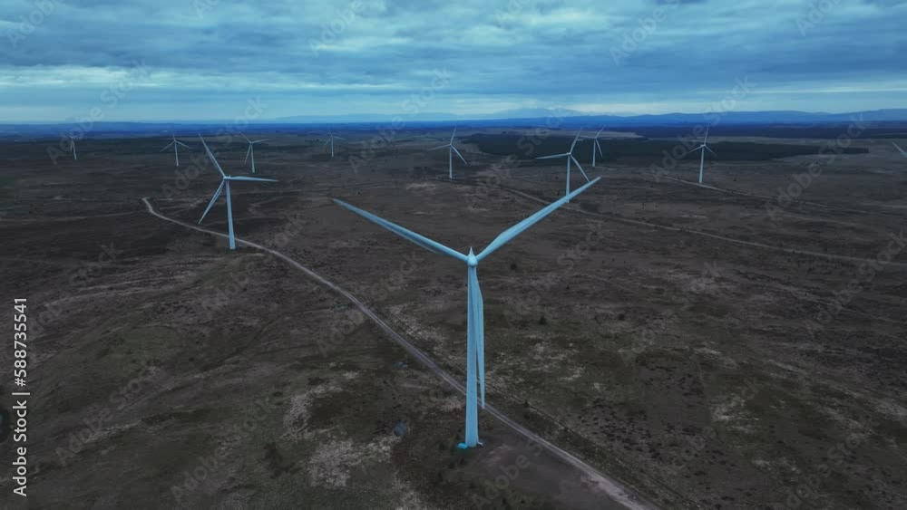 Aerial closing shot of wind mills turning and generating electricity next to a lake Aerial closing shot of wind mills turning and generating electricity next to a lake