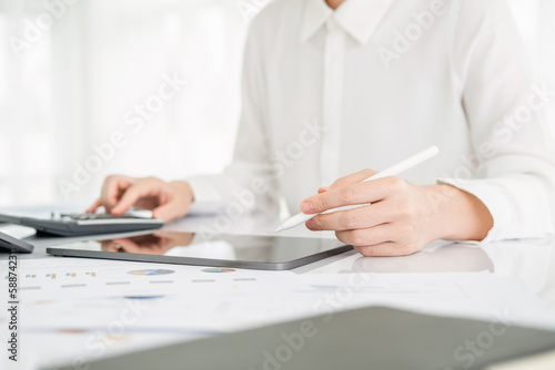 Modern business woman using calculator and tablet in workstation.