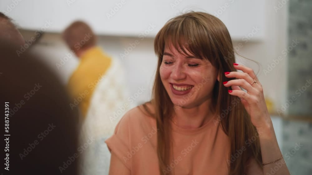 Family has dinner together in kitchen. Husband entertains wife with funny stories and woman laughs happily covering face with palm on blurred background closeup
