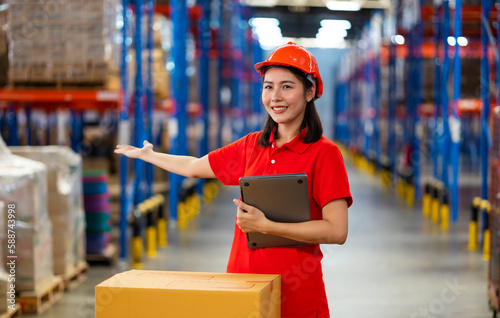 female employee proudly presents the company workplace. Warehouse female staff worker standing by goods shelf working in large warehouse factory. hands to the side for inviting to come