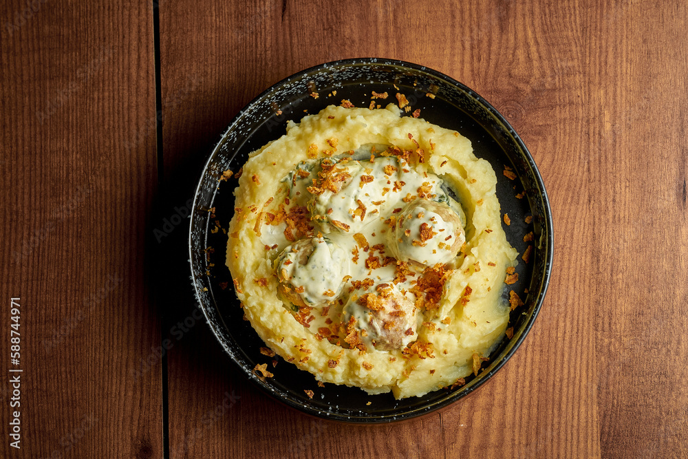 Mashed potatoes and chicken meatballs with cream sauce. Wooden background Mashed potatoes and chicken meatballs with cream sauce. Wooden background