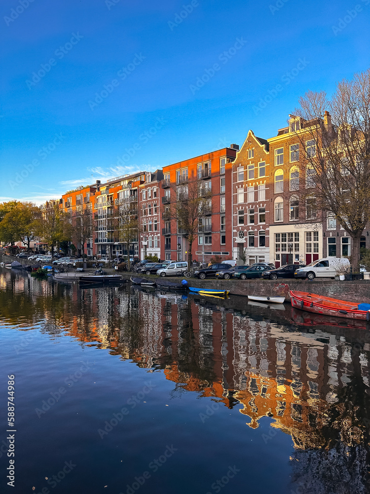 Amsterdam canal view with boats and bicycles at sunset, Netherlands