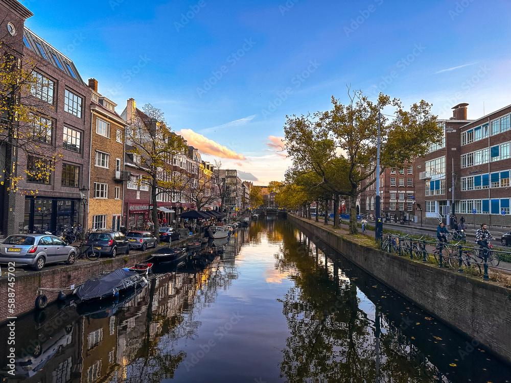 Amsterdam canal view with boats and bicycles at sunset, Netherlands