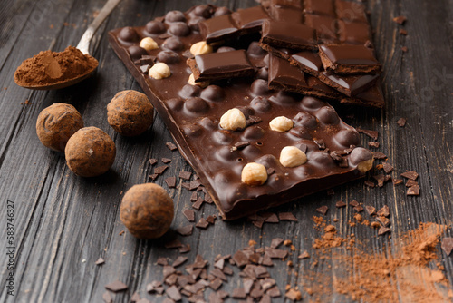 Handmade chocolate, cocoa powder in a spoon and chocolate truffles on a dark wooden background.