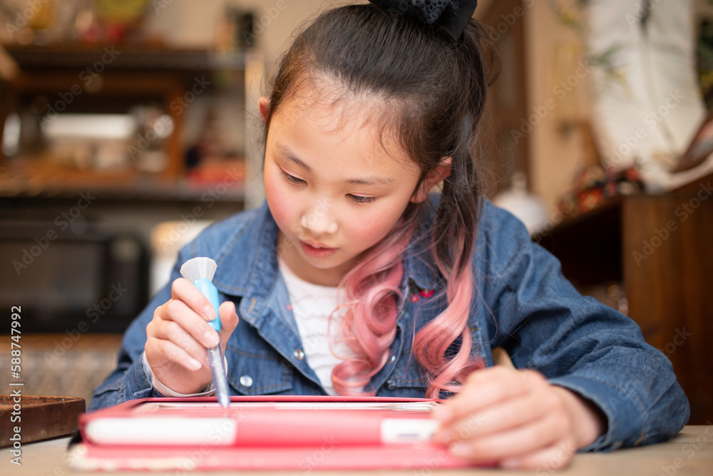 自宅でタブレット学習をするピンクの髪色の女の子 自宅でタブレット学習をするピンクの髪色の女の子