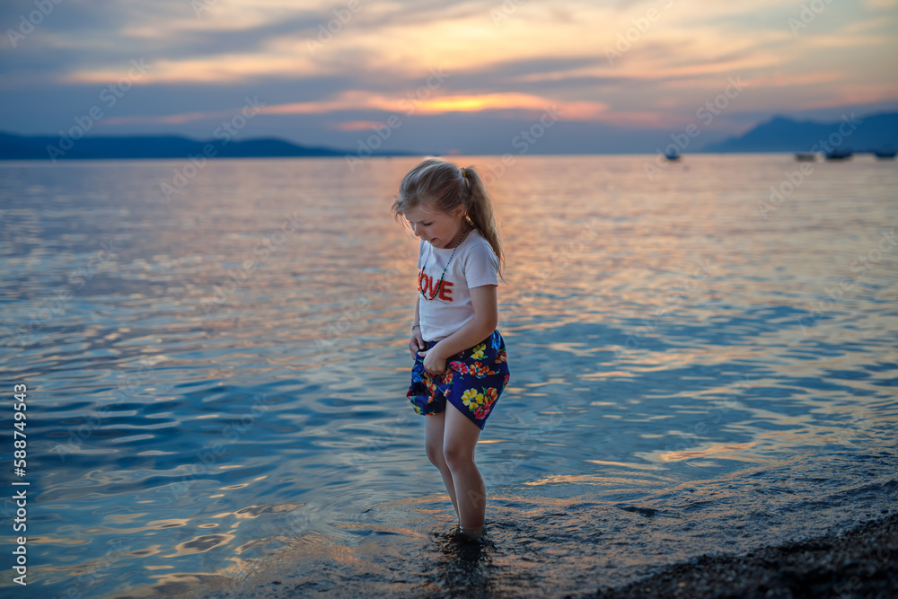 Little girl walking on beautiful ocean beach. Happy preschool child play by sunset on sea beach. Family vacations with children in summer. Little girl walking on beautiful ocean beach. Happy preschool child play by sunset on sea beach. Family vacations with children in summer.