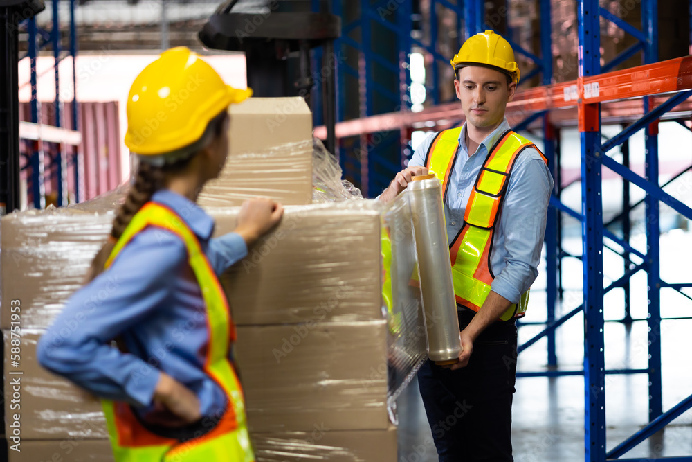 Caucasian team man and woman worker working at warehouse factory. Warehouse staff worker are helping to wrap the shock absorber on the container box Caucasian team man and woman worker working at warehouse factory. Warehouse staff worker are helping to wrap the shock absorber on the container box