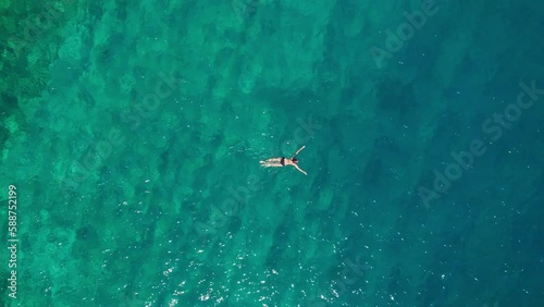 Aerial top down view of a woman swimming in a turquoise sea water in Greece.  photo