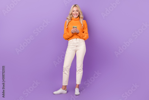 Full body photo of cheerful pretty lady hold use smart phone chatting isolated on violet color background