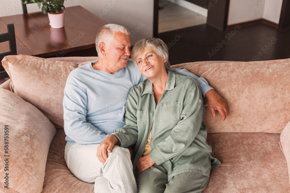 Portrait of a beautiful senior couple embracing each other, sitting on the couch at home Portrait of a beautiful senior couple embracing each other, sitting on the couch at home