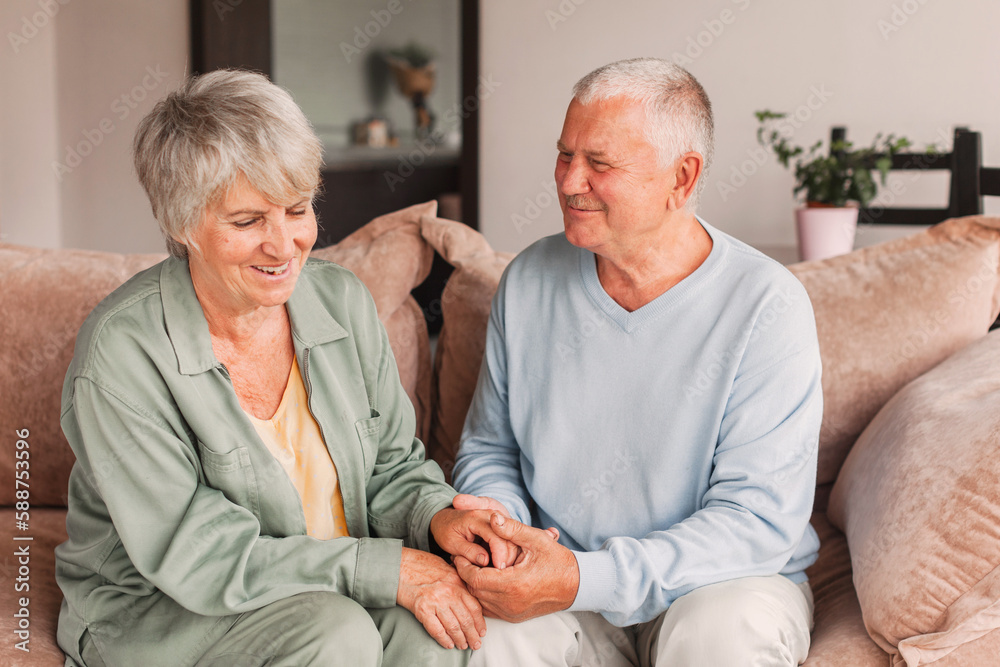 Portrait of a beautiful senior couple embracing each other, sitting on the couch at home Portrait of a beautiful senior couple embracing each other, sitting on the couch at home