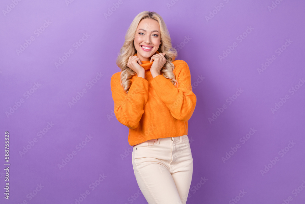 Photo of optimistic nice looking girl with stylish hairdo dressed orange sweater hands hold neck isolated on purple color background Photo of optimistic nice looking girl with stylish hairdo dressed orange sweater hands hold neck isolated on purple color background