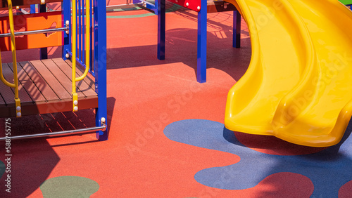 Foto Yellow Slide with Playground Climbing Equipment on Colorful Rubber Floor in Outd