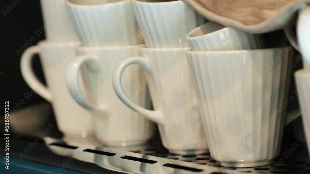 Many rows of white coffee cup with saucer and teaspoon on table and coffee maker background Many rows of white coffee cup with saucer and teaspoon on table and coffee maker background