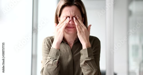 Tired female manager rubbing dry irritated eyes and feeling tired eyes. Eye strain and migraine after computer work