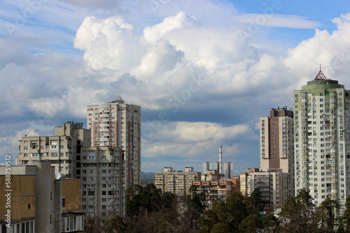 High-rise residential buildings and an industrial plant with a pipe around a green park in a modern city