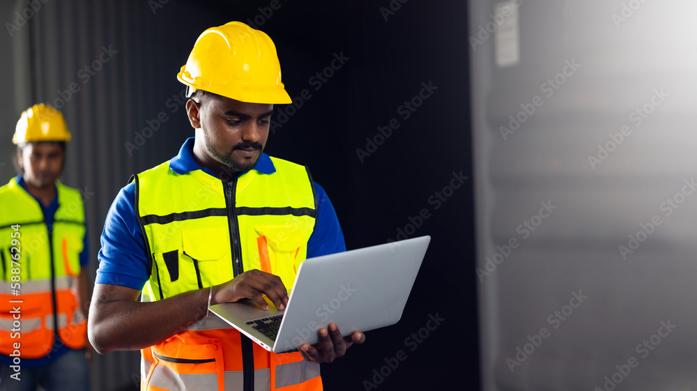 Portrait warehouse indian worker wearing safety hardhats helmet working on laptop computer in warehouse of Wholesale Merchandise. shelves, pallets and boxes Portrait warehouse indian worker wearing safety hardhats helmet working on laptop computer in warehouse of Wholesale Merchandise. shelves, pallets and boxes
